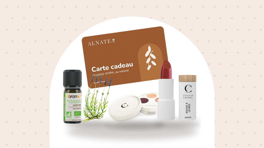 Carte cadeau Alnatea, palette et rouge à lèvres Couleur Caramel et huile essentielle Florame sous une arche blanche sur fond rosé